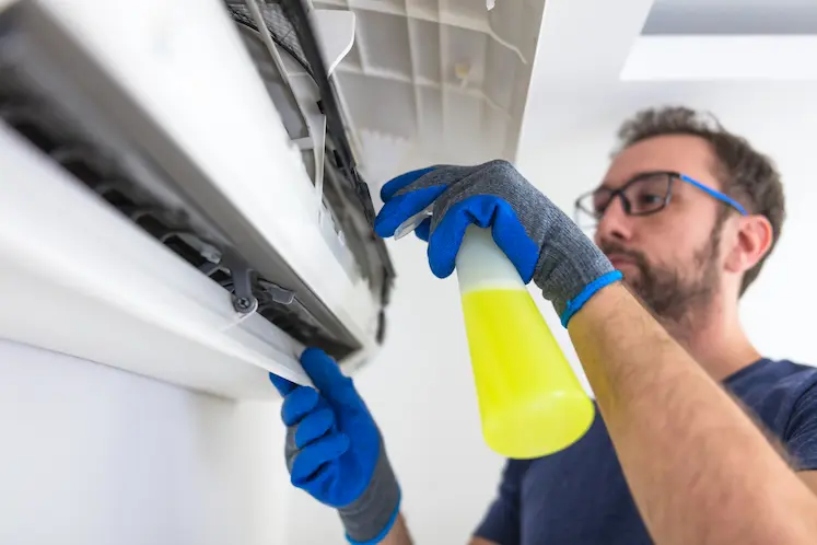 tecnico pulisce il condizionatore interno con spray detergente in appartamento veneto