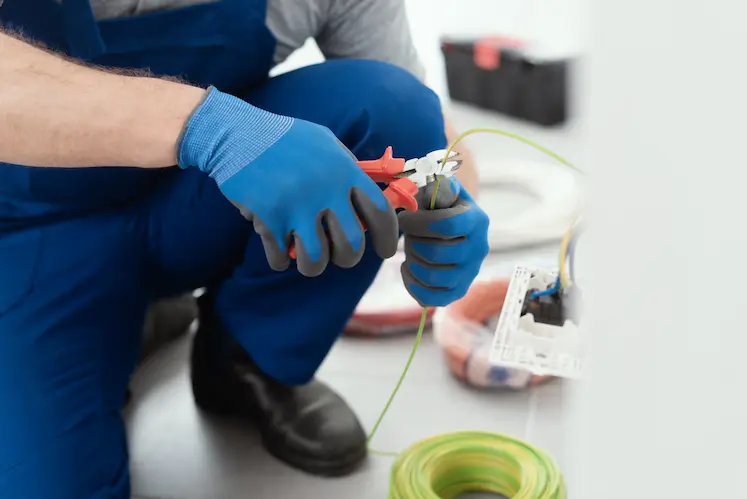 elettricista d'urgenza lavora sui cavi elettrici con pinze tagliafili professionali