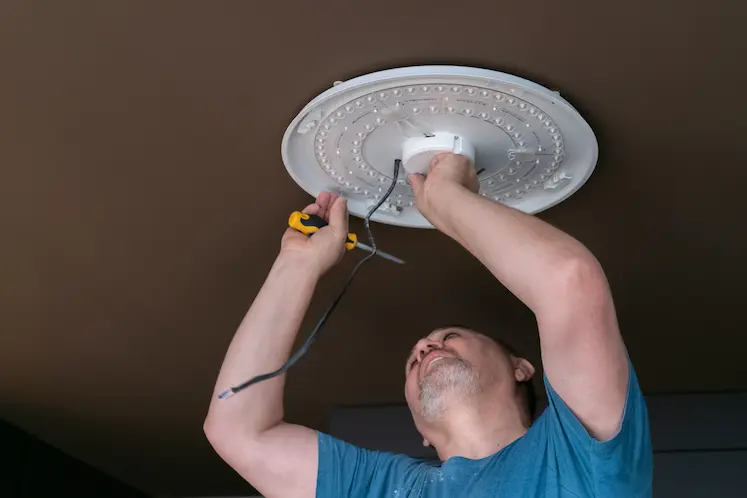 tecnico installa nuovo lampadario sul soffitto in abitazione storica toscana