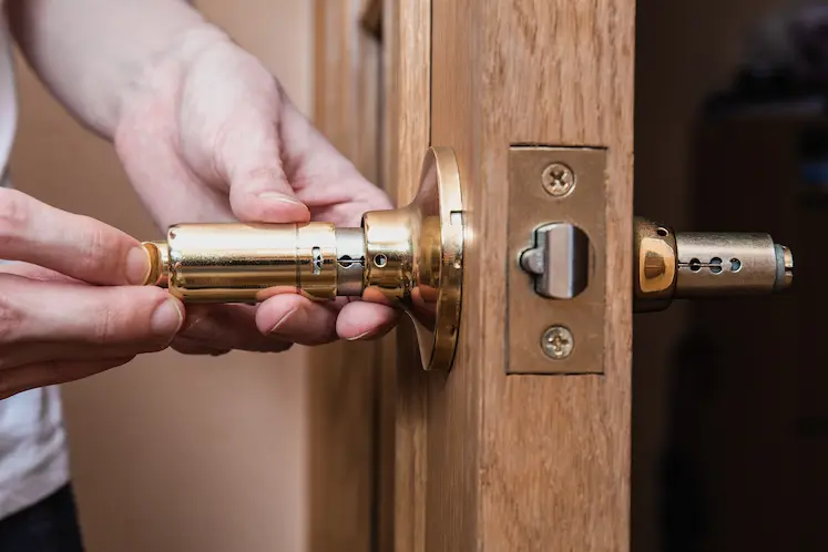 Mani che installano una nuova serratura in ottone su una porta ad Ancona