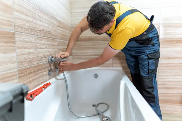 Idraulico al lavoro sul rubinetto nel bagno di casa durante un intervento ad Ancona